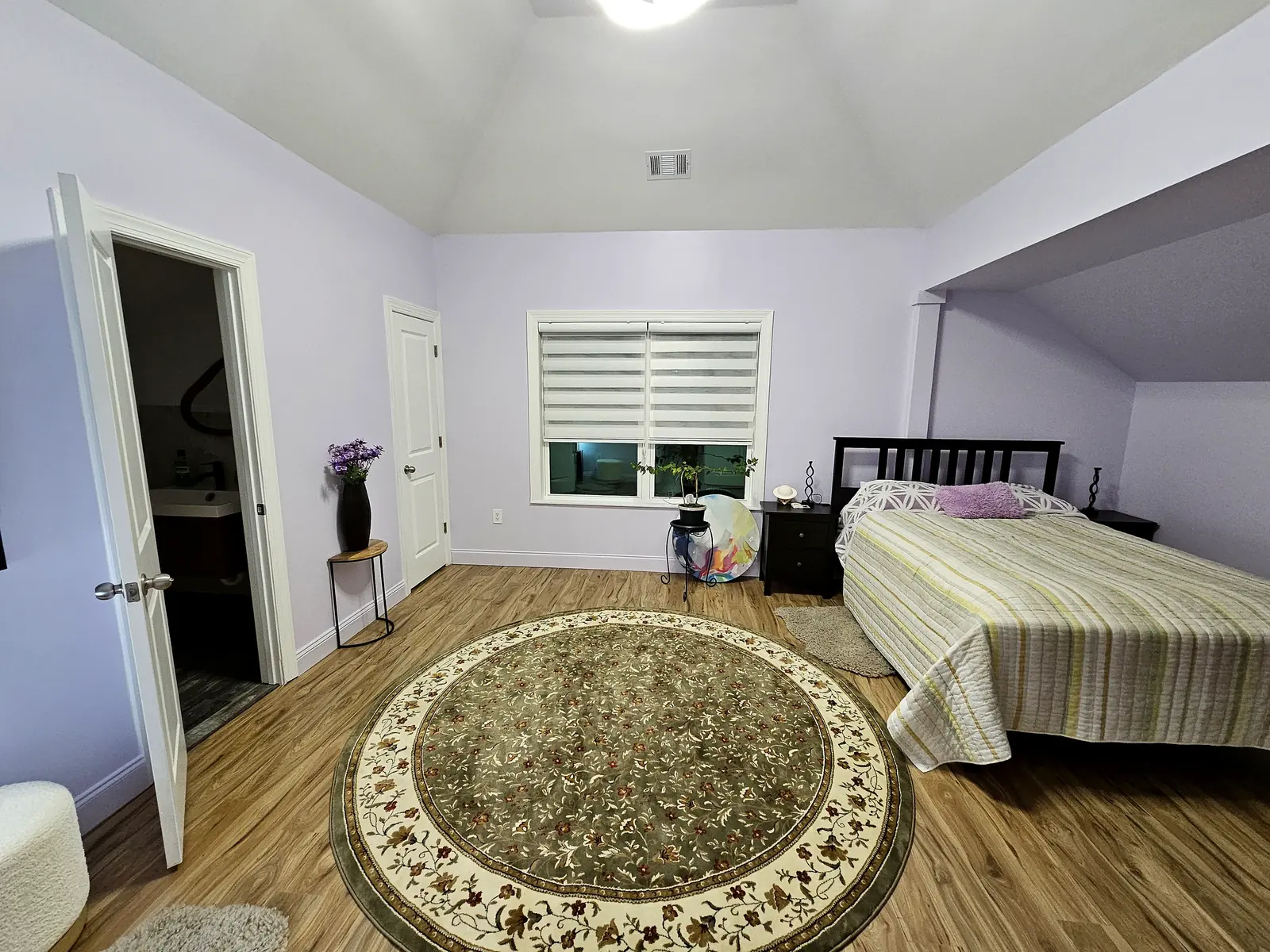 Painted bedroom with hardwood floors and round rug
